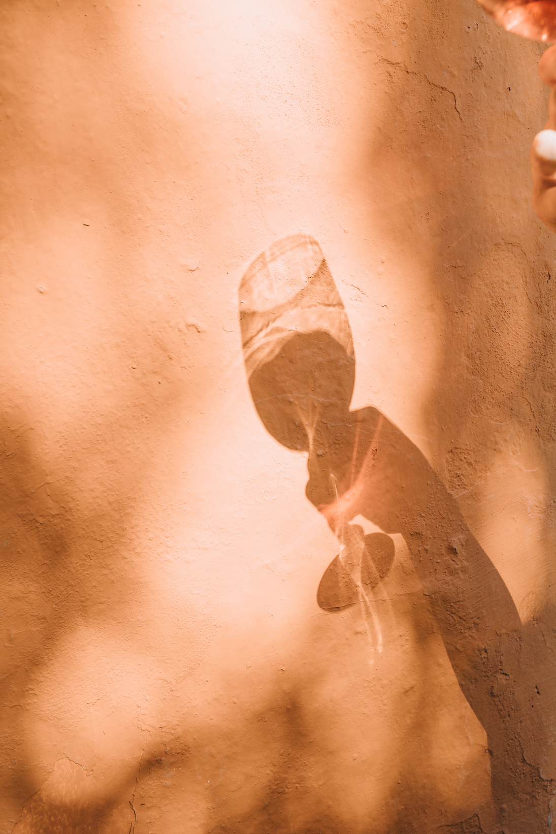 Shadow of a Person's Hand Holding a Glass of Wine